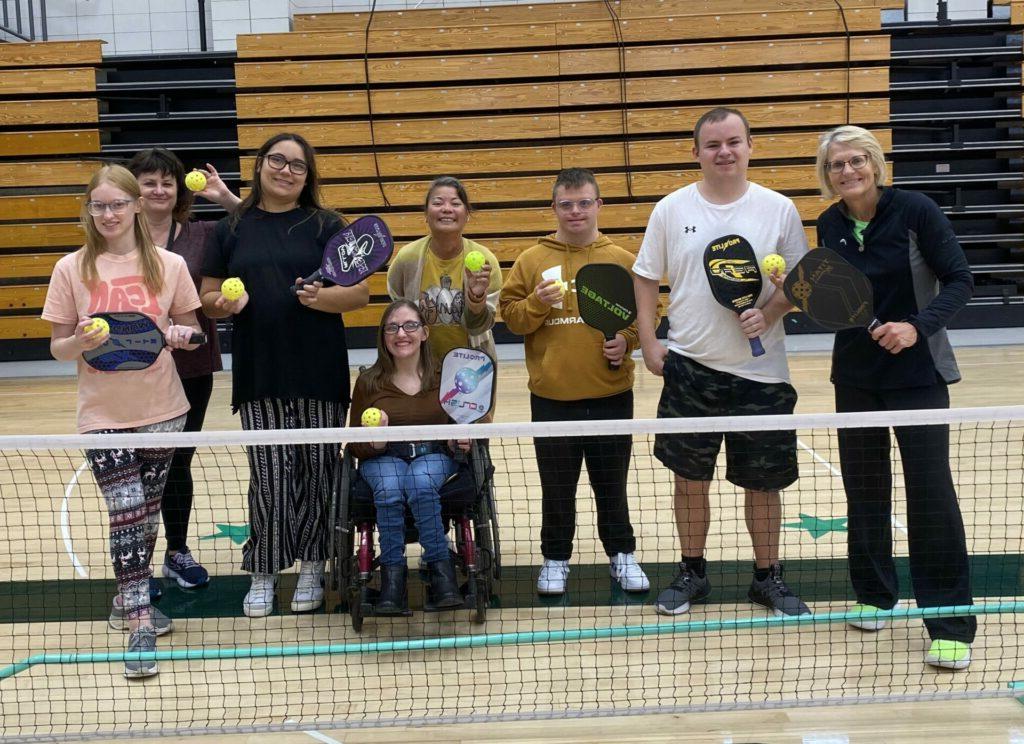 终身大学 students posing with pickleball coach